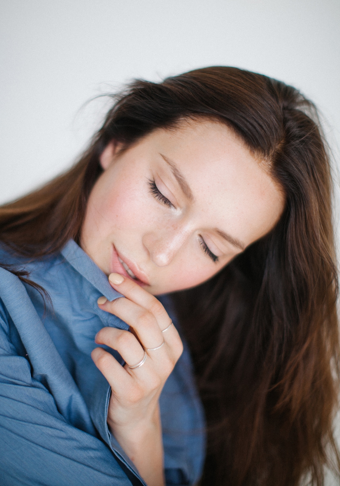 Mujer tocándose los labios suavemente mientras inclina la cabeza hacia la derecha y cierra los ojos