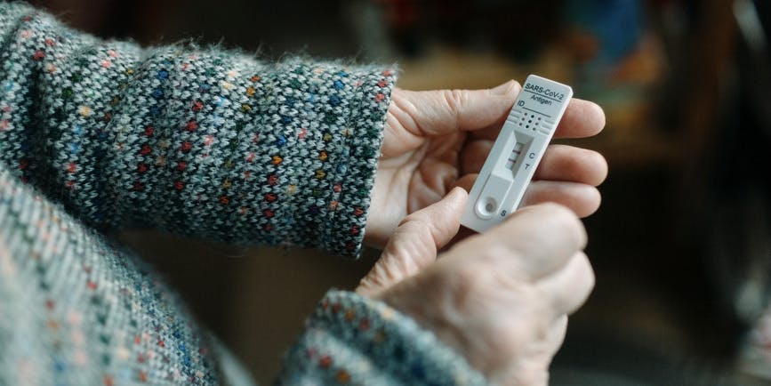 Las manos de una persona irreconocibles comprueban el resultado positivo de una prueba rápida de Covid en casa. Tiene la prueba en sus manos bajo la luz natural