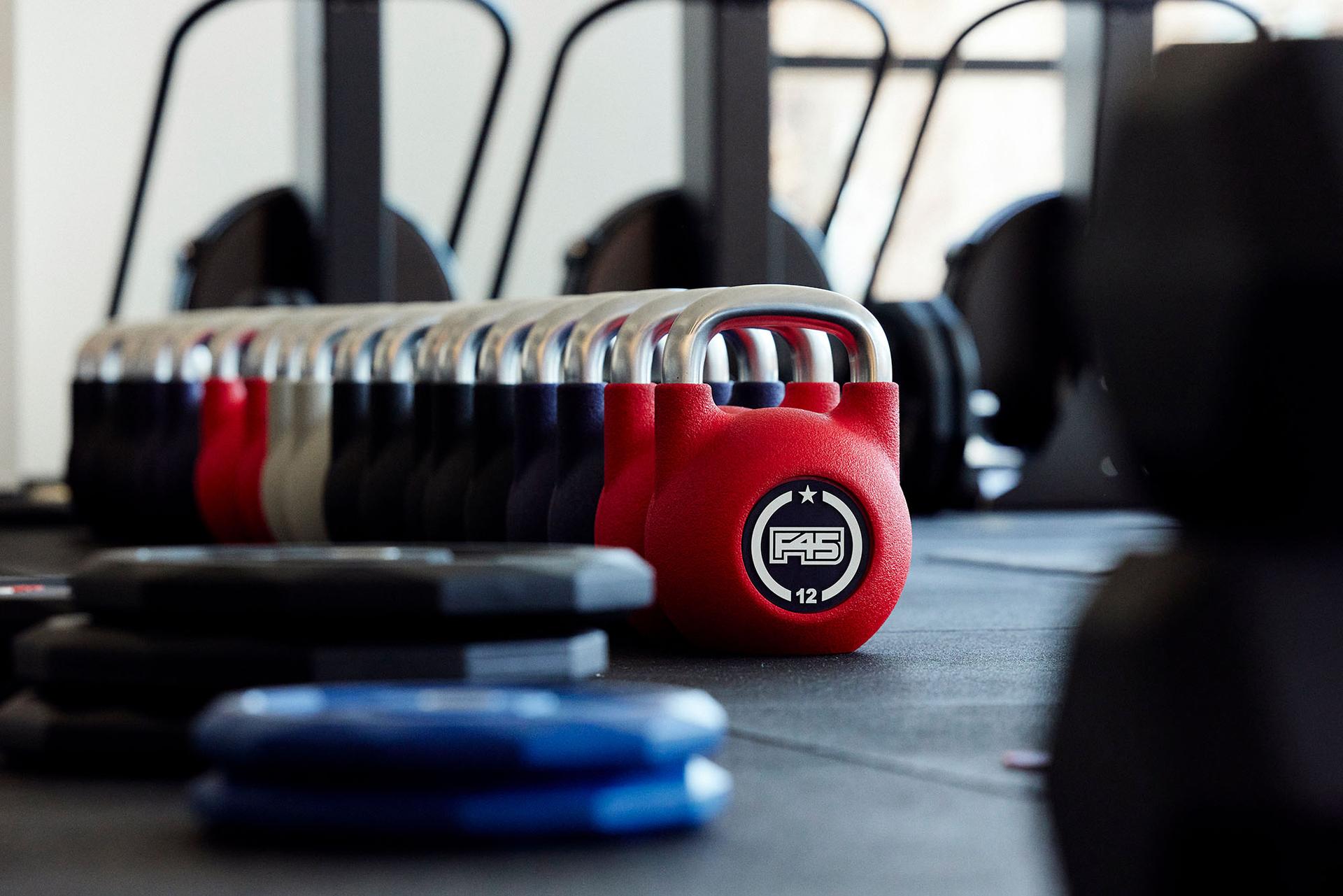 Pesas de entrenamiento F45 alineadas en fila en el suelo de un gimnasio