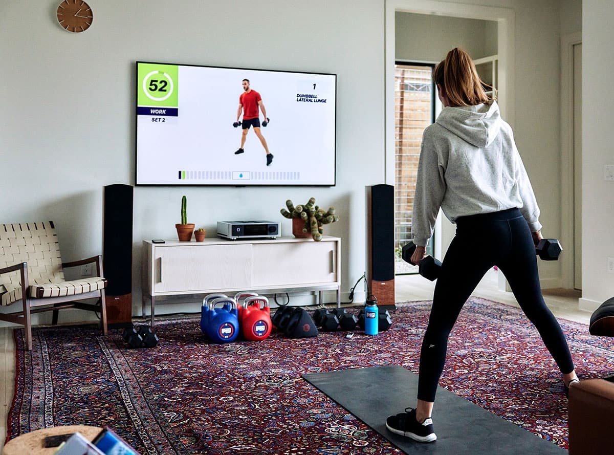 Mujer haciendo ejercicio en casa con el contenido de fitness F45 Training