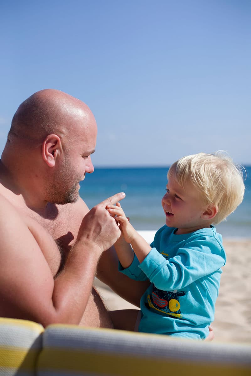 Padre con sobrepeso jugando con su hijo en la playa