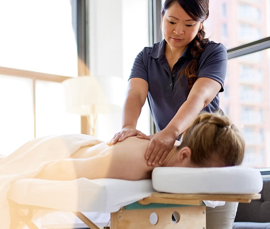 A woman enjoys a massage while lying on a bed.