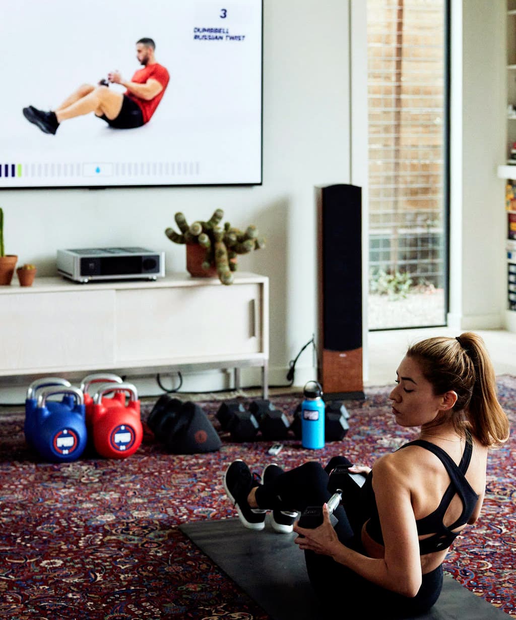 Mujer haciendo ejercicio en casa con el contenido de fitness F45 Training